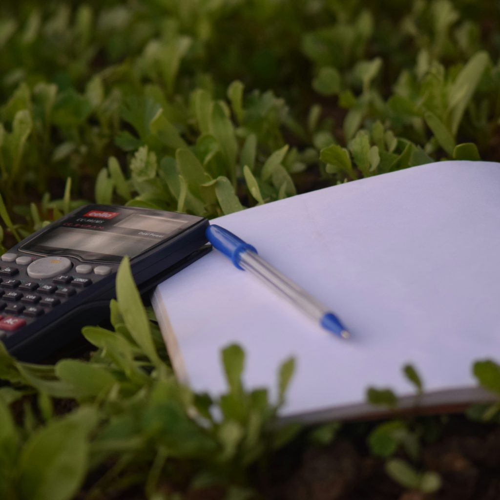 Calculator, pen and a book on grass